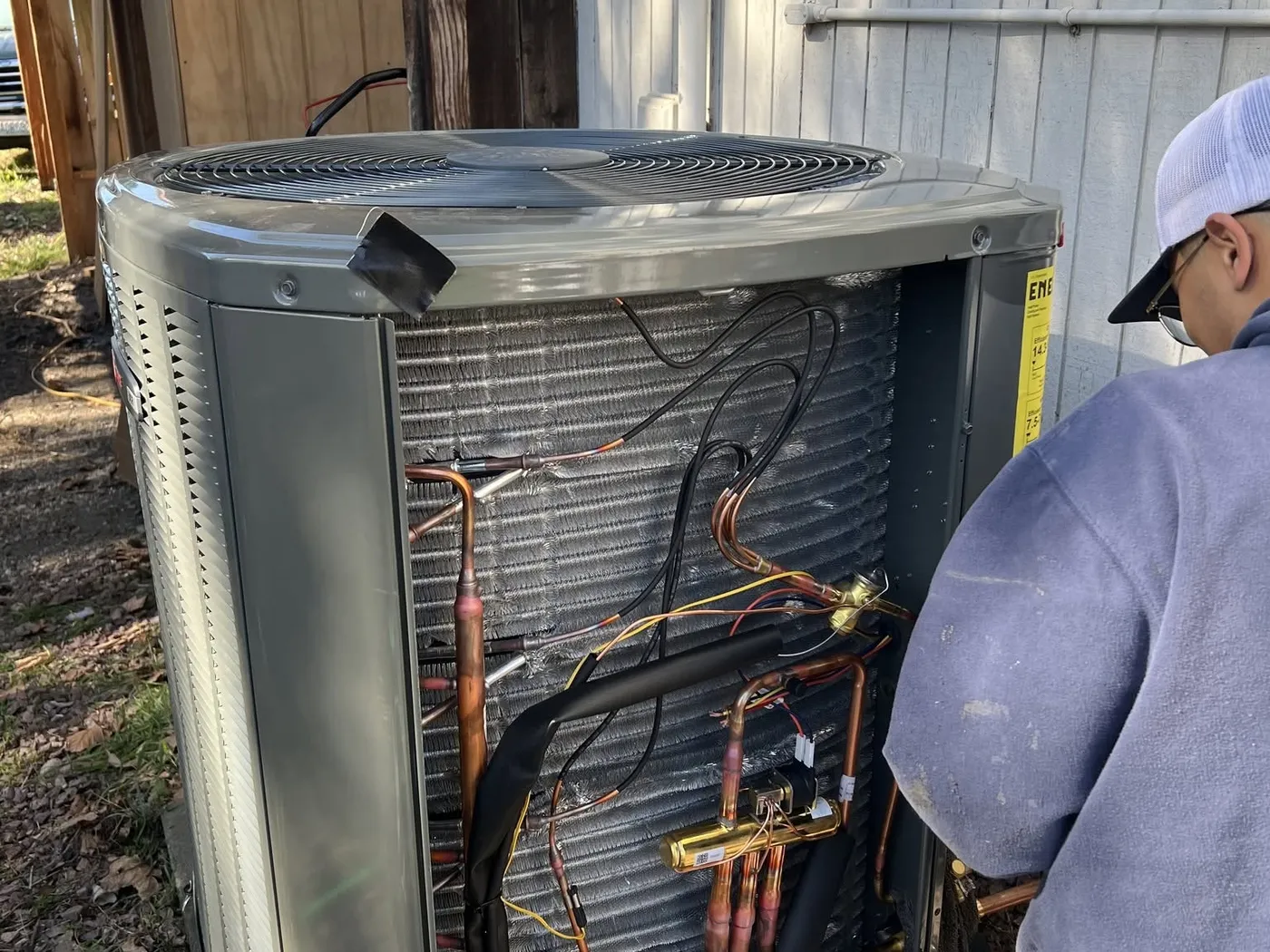 A Dayco technician beside a Trane outdoor unit with its service panel open
