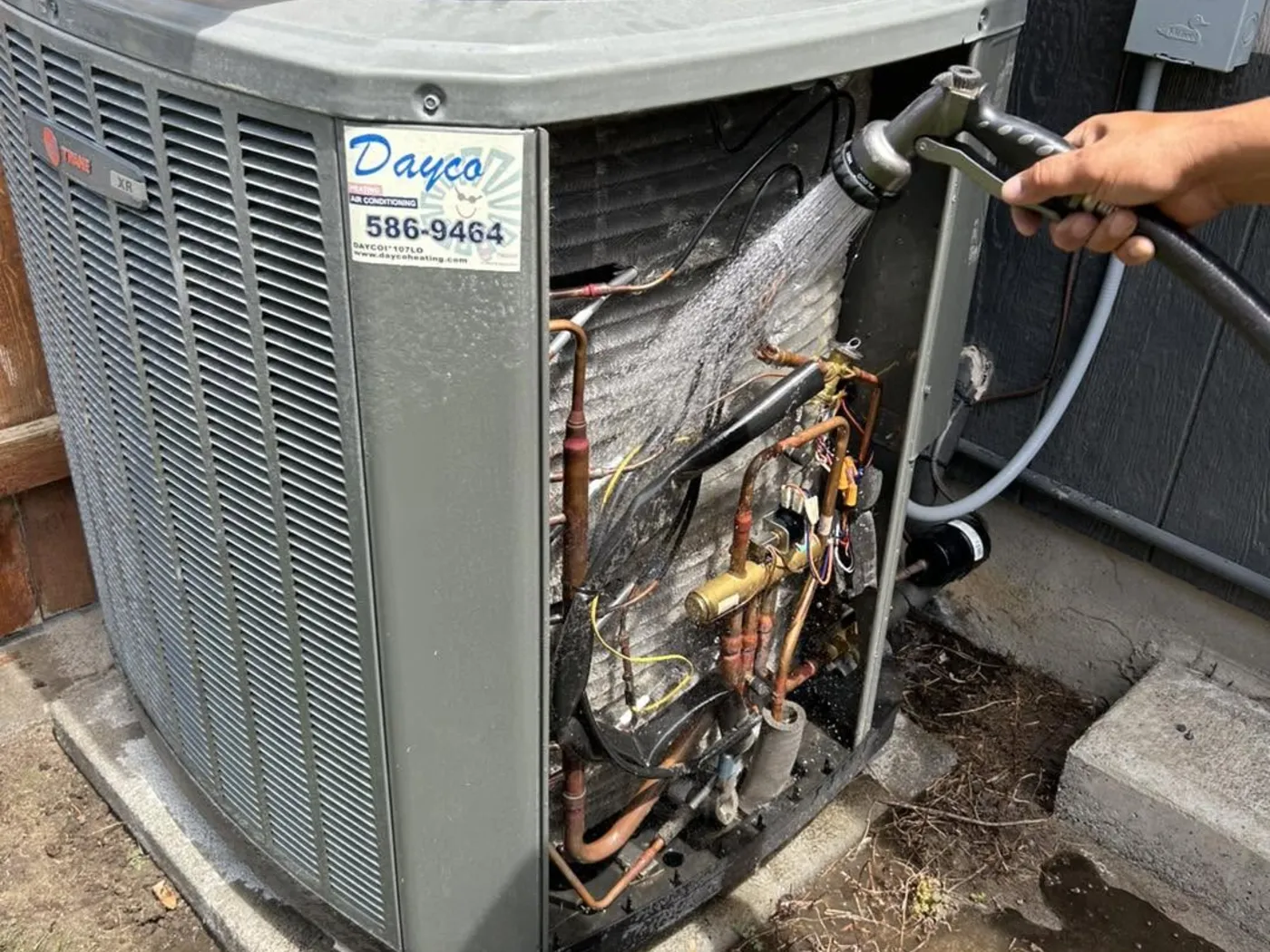 A Dayco technician checking refrigerant pressures on a Trane outdoor unit